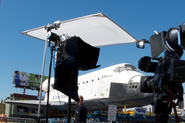 Behind some TV camera equipment