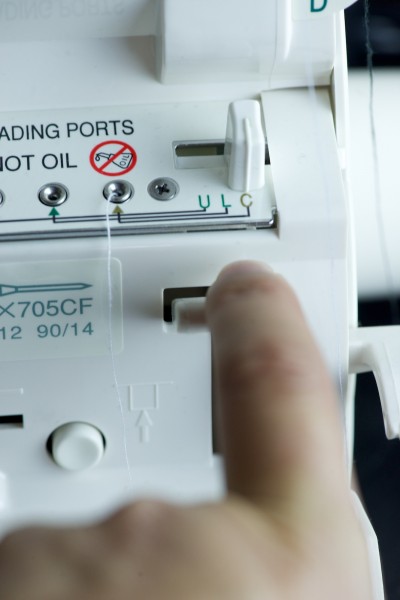 Pressing the air lever to make the thread get sucked into the machine